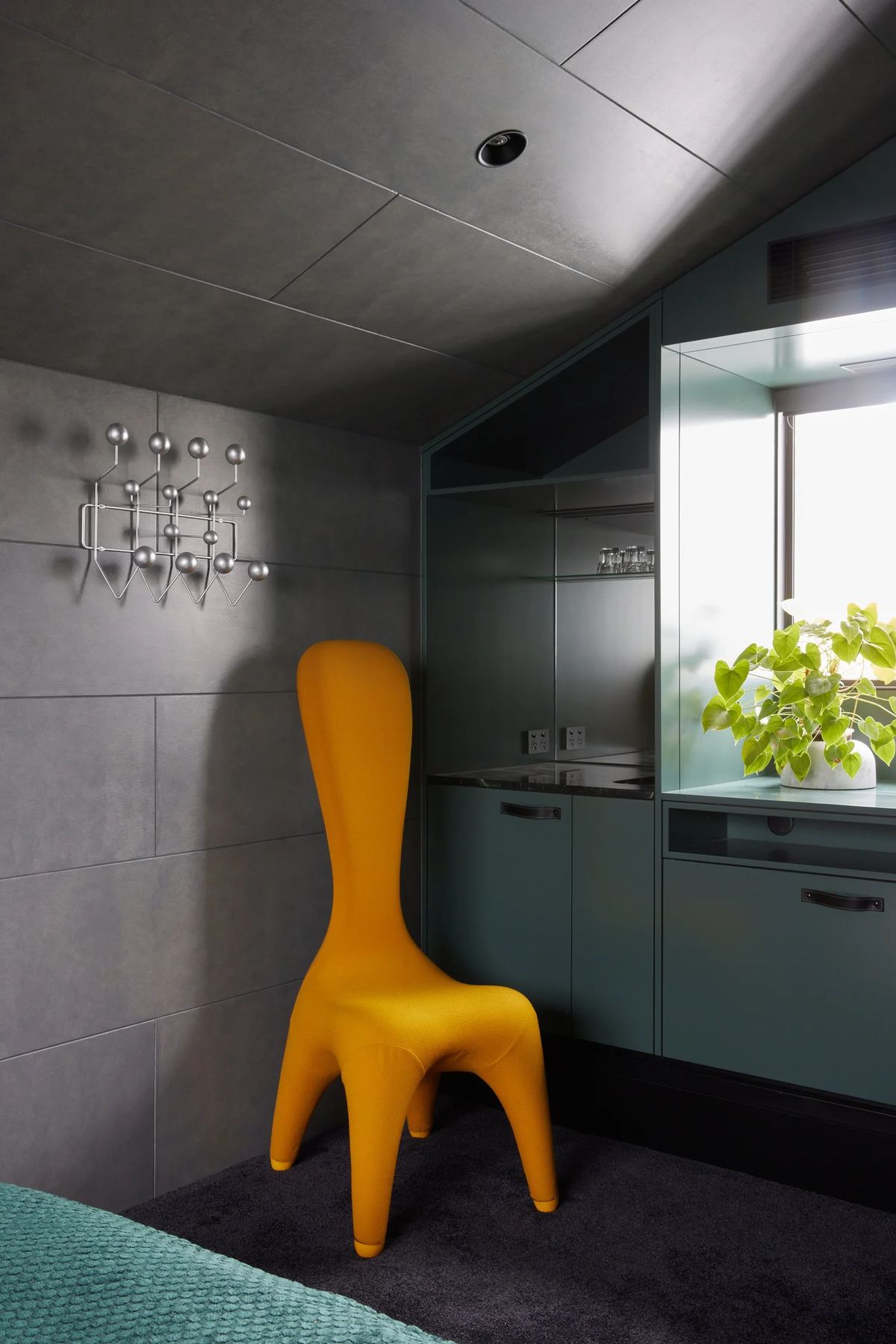 Deep green kitchen cabinetry with a yellow chair