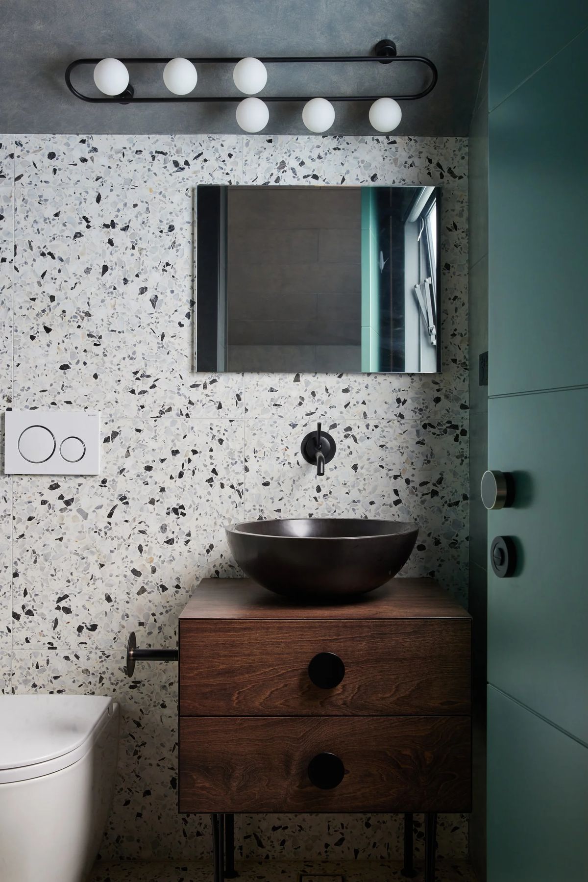 Terrazzo powder room with black basin and walnut vanity
