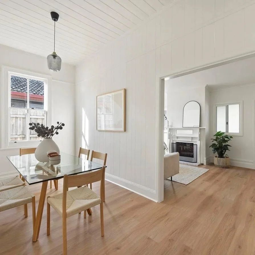 Styled dining space with timber floors and a fireplace beyond