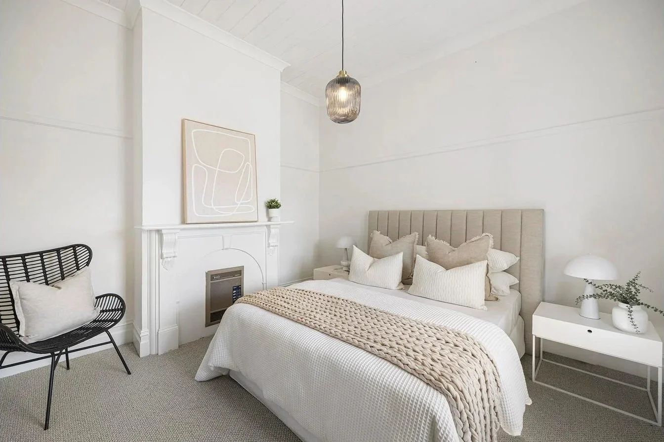 Bedroom after, styled in white with the restored fireplace