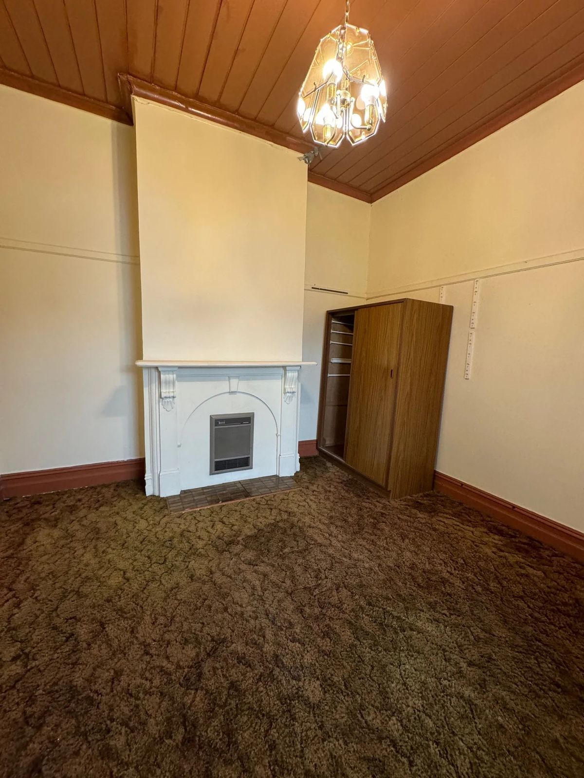 Living room before with brown carpet and dated fireplace