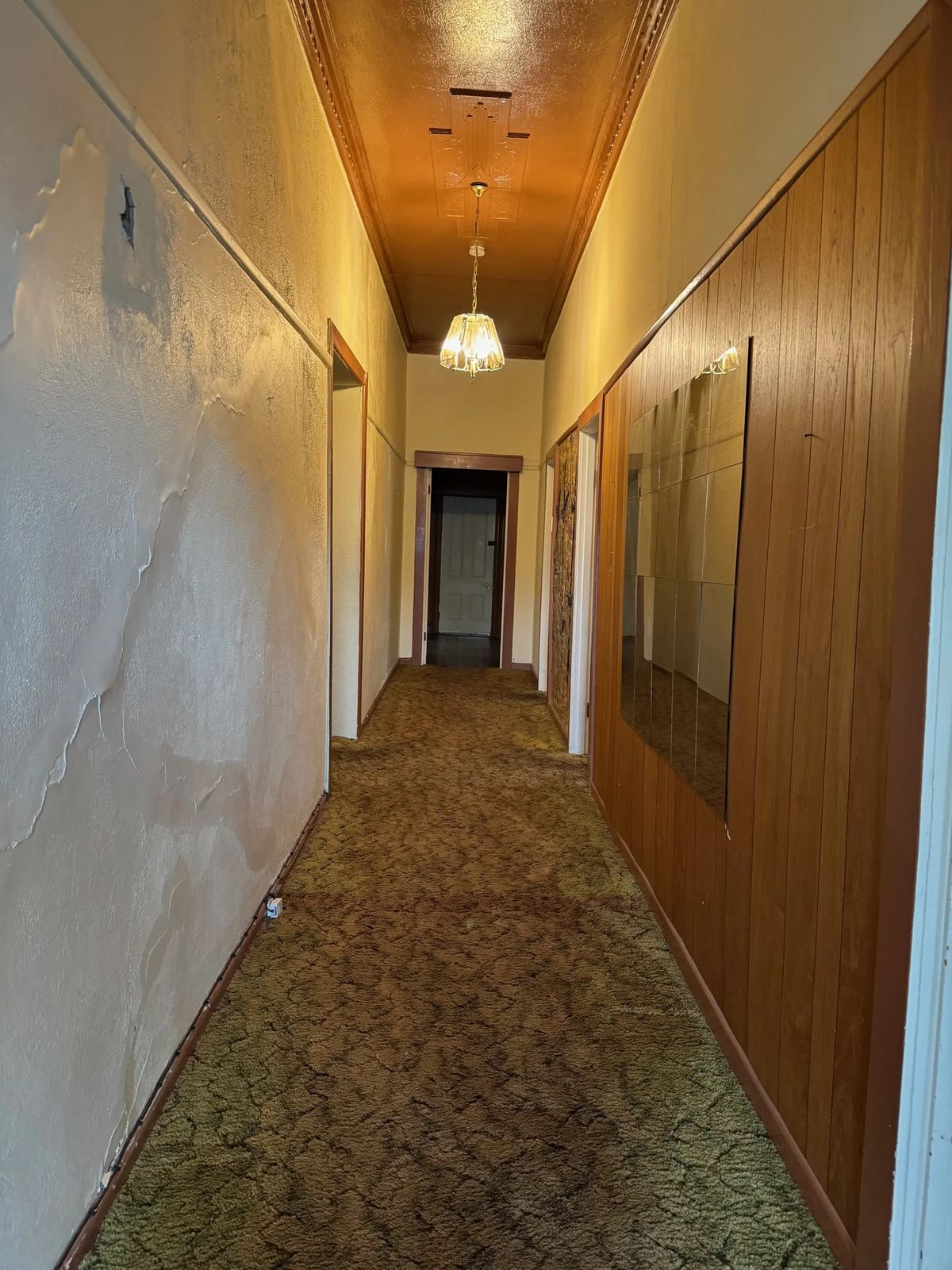 Hallway before: timber panelling, worn carpet and dated paint