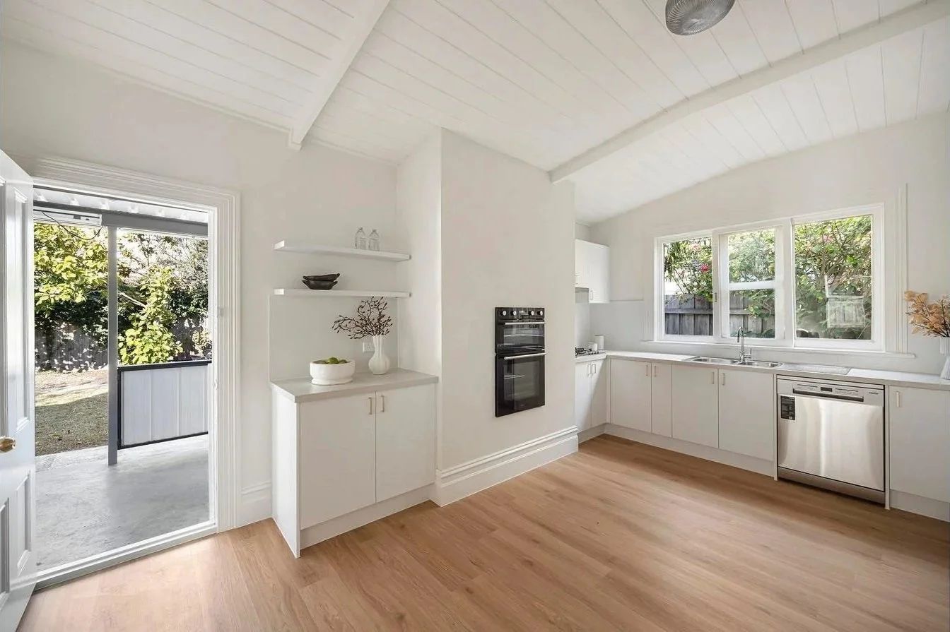 New white kitchen with timber floors and garden outlook