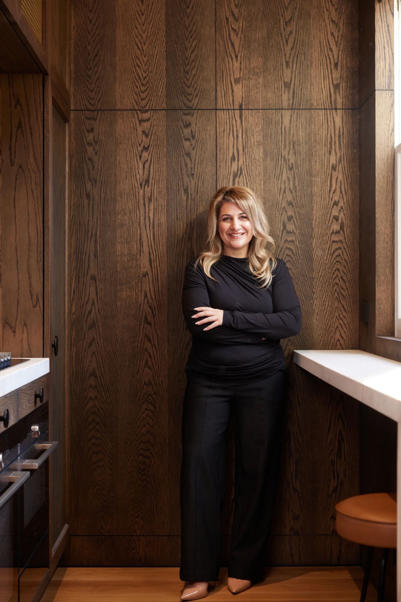 Nina, founder of Maintainwell, standing in a finished timber-lined kitchen